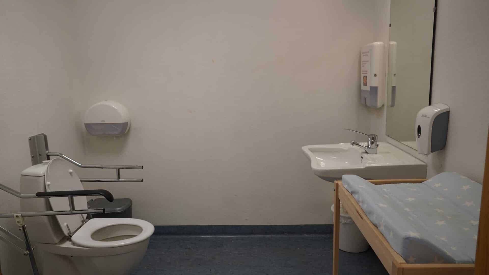 The accessible toilet at Kafe Mat & prat has armrests and a long sink.