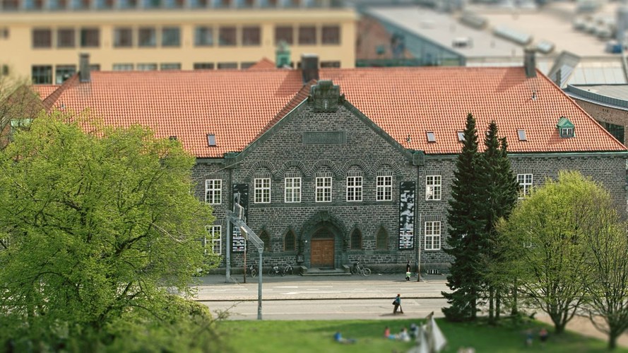 Bergen Public Library Main Library's building with a red-tiled roof, arched windows, and a central wooden door, photographed from the direction of Lille Lungegårdsvannet.